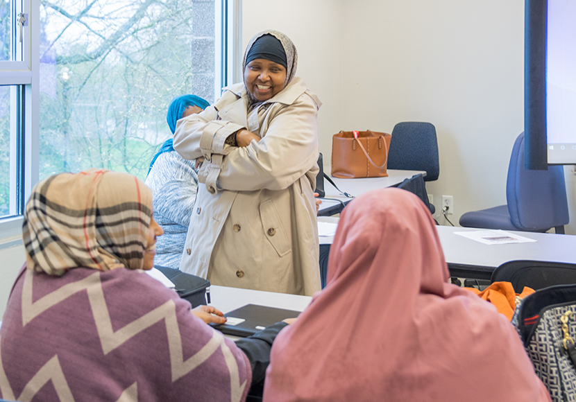 Person standing and talking to two seated people
