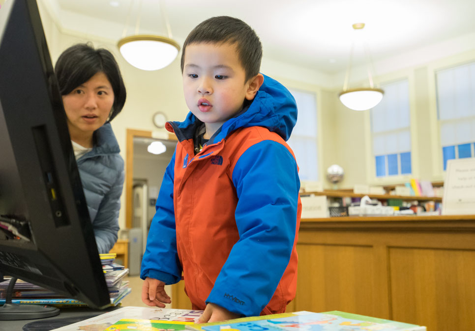 Family at self-checkout station at the Green Lake Branch