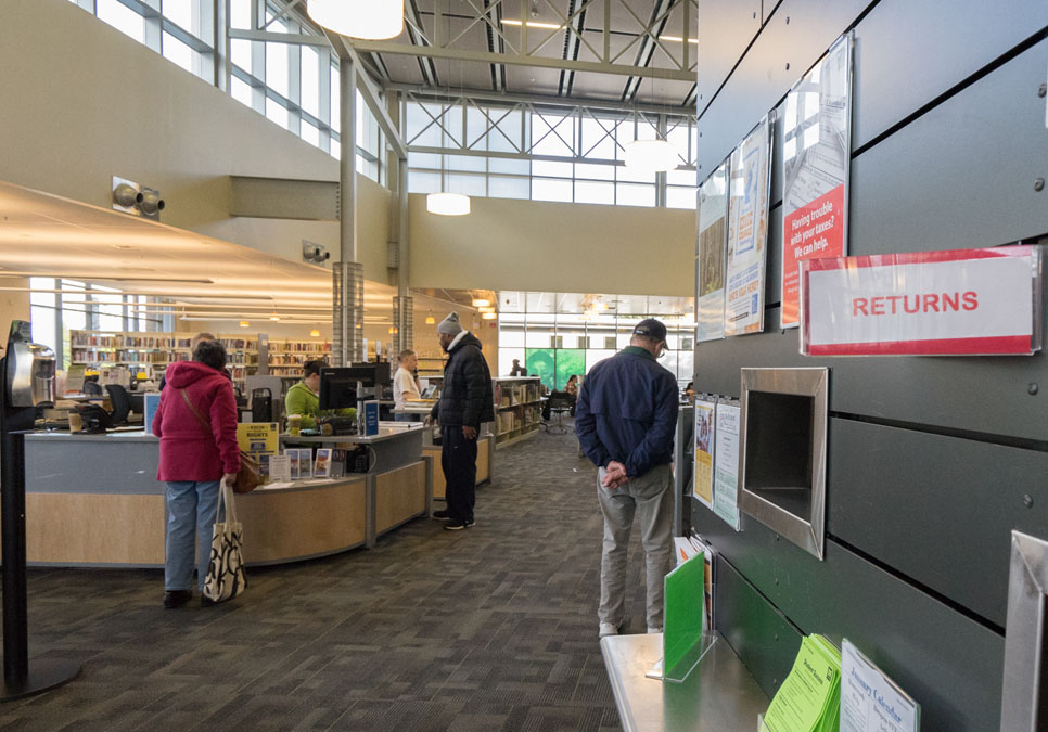 Library patrons at the service desk area at the Greenwood Branch