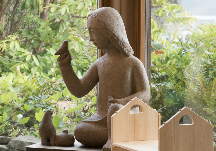 Sculpture of a figure looking at a bird perched on its hand.