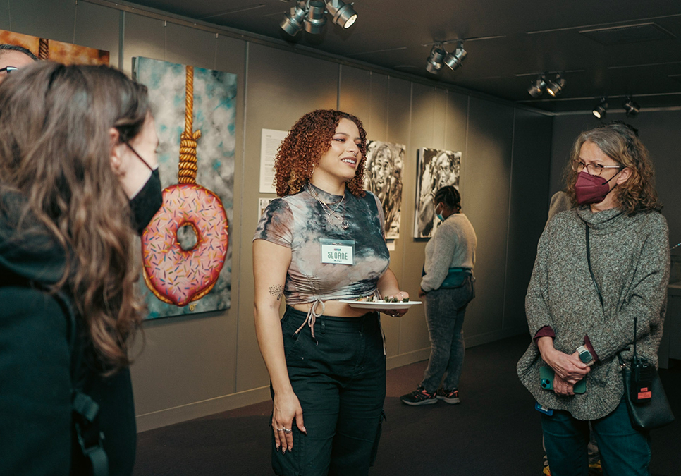 Artist Sloane Miller discussing her art work at the 2022 Art Exhibit opening at the Central Library.