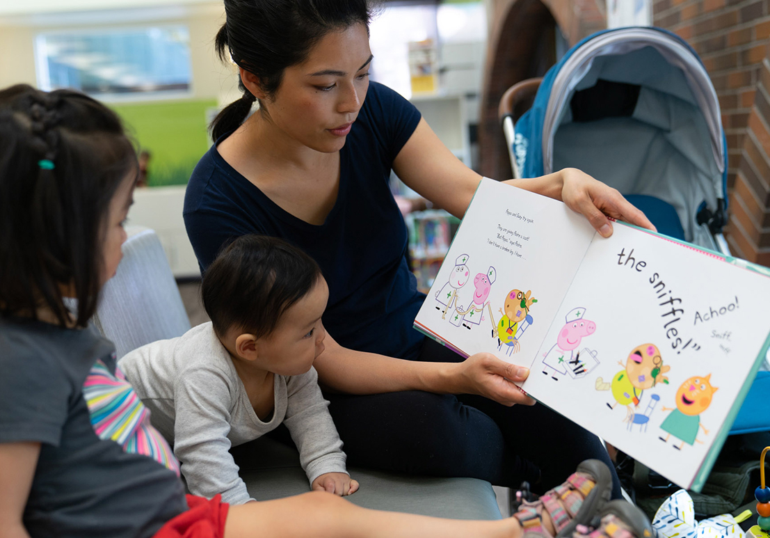 Woman showing pictures in a book to children.