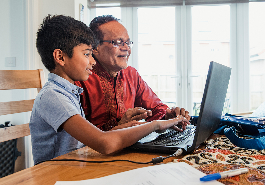 Adult and child operating a laptop computer.