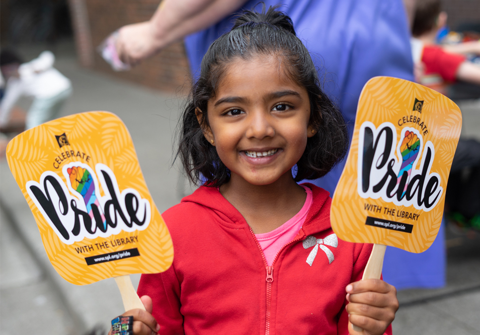 Library patron holding SPL Pride fans at the Seattle Pride Parade in 2019