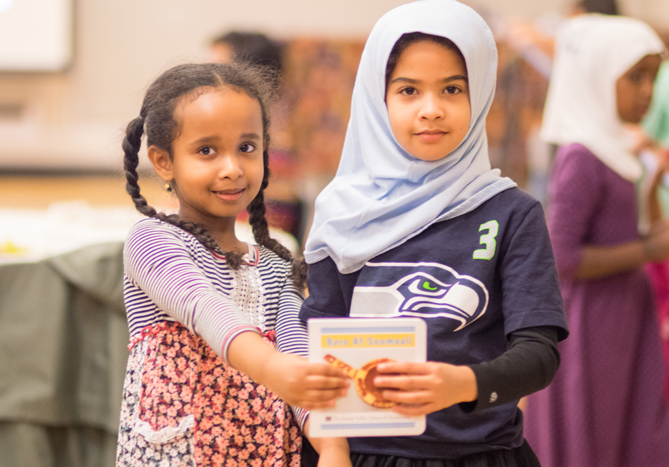 Young girls showing their Somali letter book, which was created in partnership with the local Somali community